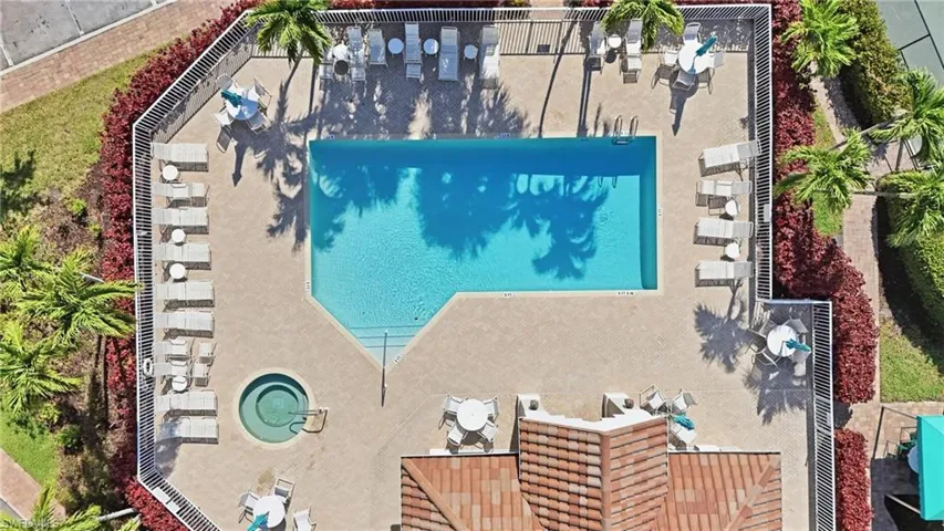Expansive outdoor amenity area featuring a rectangular swimming pool, integrated spa, and surrounding paved deck