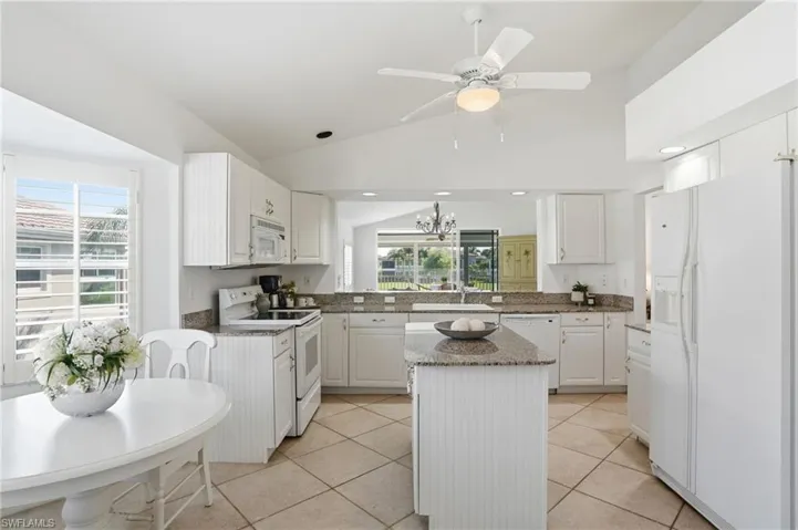 Kitchen featuring white cabinetry, granite countertops, a central island, and tiled flooring