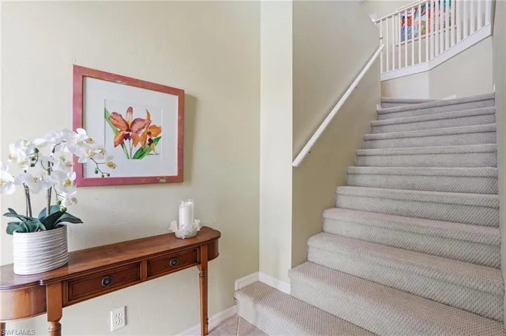 Carpeted staircase with white railing and neutral wall tones