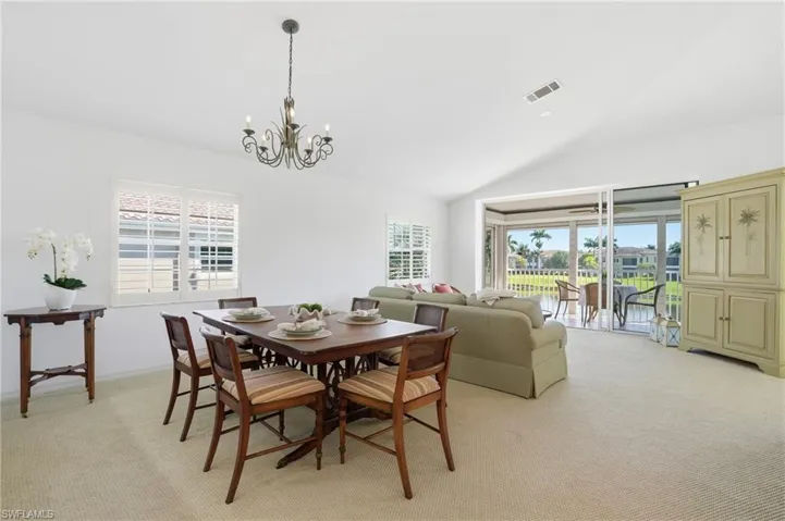 Vaulted ceilings crown this space featuring a chandelier light fixture and carpet flooring