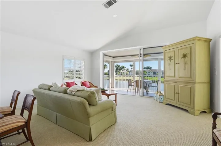 Spacious living area featuring a vaulted ceiling and textured carpet flooring