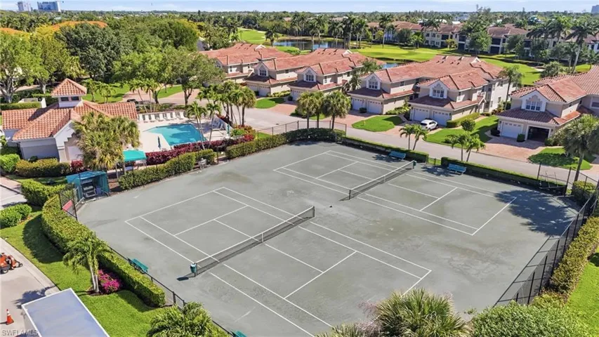 Dual tennis courts with perimeter fencing and lush landscaping