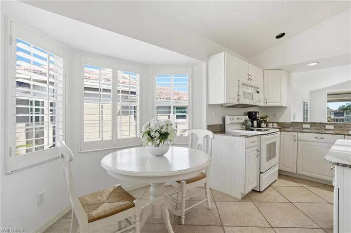 Kitchen featuring white cabinetry, light-toned countertops, and a bay window with plantation shutters