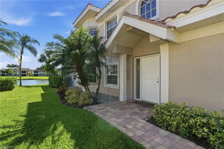Stucco exterior with a tiled roof, an inviting covered entry, and a paver walkway