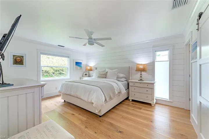 Bedroom featuring ceiling fan, ornamental molding, multiple windows, and light hardwood / wood-style flooring