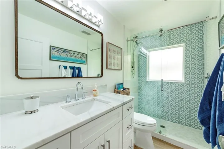 Bathroom with walk in shower, vanity, wood-type flooring, and toilet