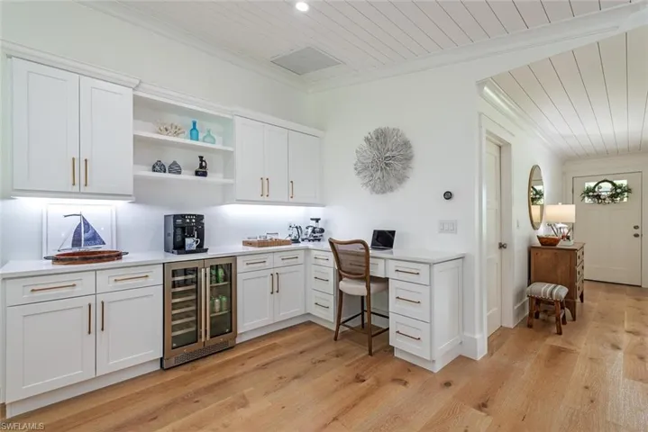 Bar with white cabinets, light hardwood / wood-style floors, wood ceiling, and wine cooler