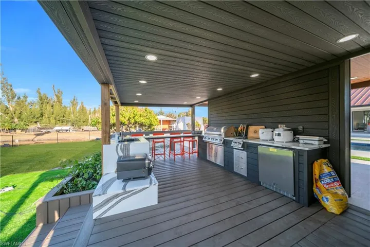 Wooden terrace with an outdoor kitchen and a lawn