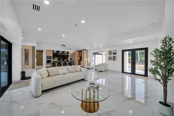 Living room featuring light marble finish flooring, french doors, and recessed lighting
