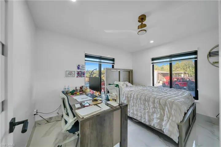 Bedroom with recessed lighting, ceiling fan, an office area, and light marble finish flooring