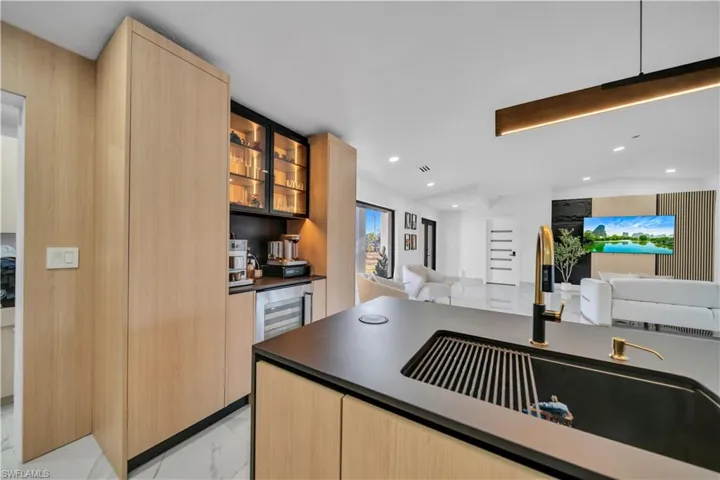Kitchen with glass fronted cabinets, light wood finish cabinets, dark countertops, lofted ceiling, and open floor plan