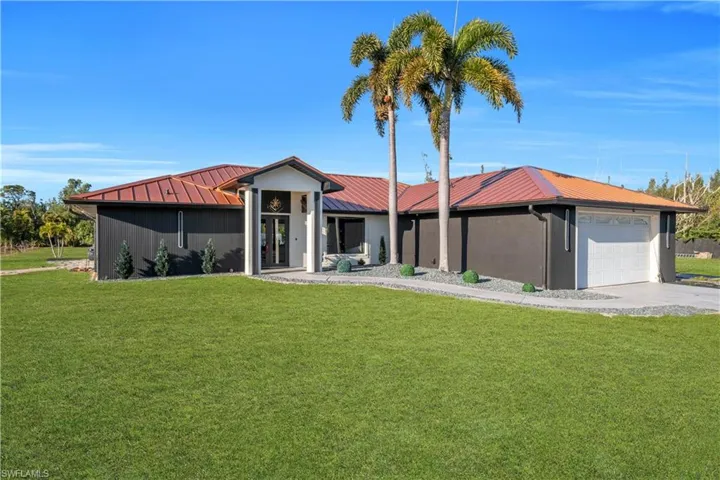 View of front of house featuring a front lawn, a metal roof, a garage, and concrete driveway