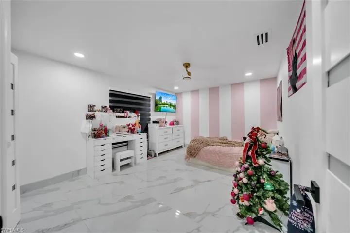 Bedroom with wallpapered walls, an accent wall, recessed lighting, ceiling fan, and light marble finish floors