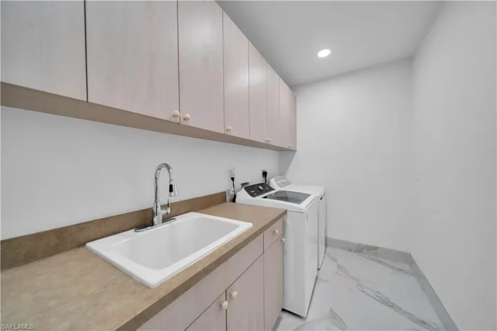 Laundry room featuring cabinet space, recessed lighting, light marble finish flooring, and independent washer and dryer