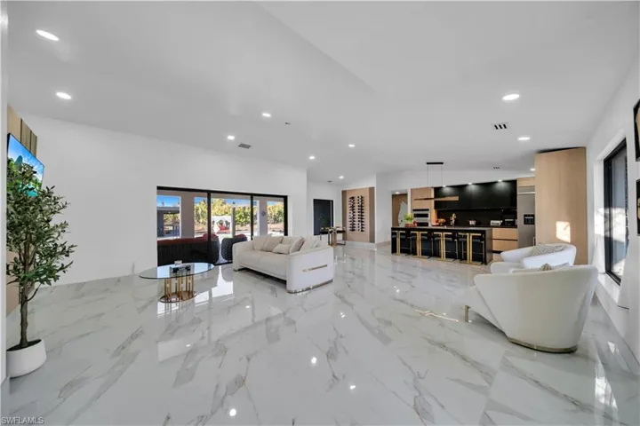 Living area with recessed lighting, a high ceiling, and light marble finish flooring