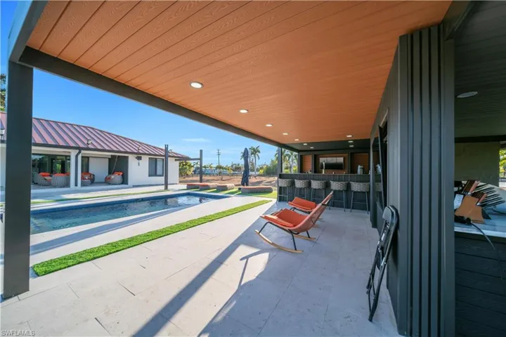 View of patio with an outdoor pool and a bar