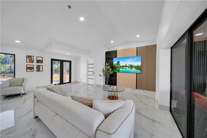 Living room featuring french doors, marble tiled floors, recessed lighting, and vaulted ceiling