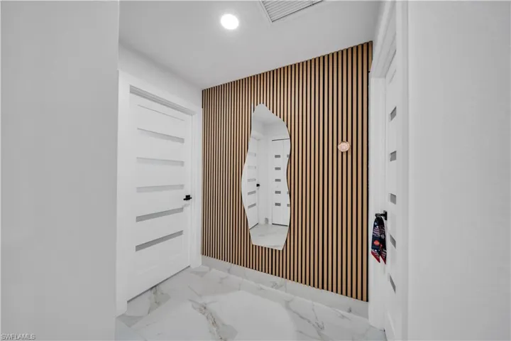 Entrance foyer featuring wallpapered walls, recessed lighting, an accent wall, and marble finish flooring