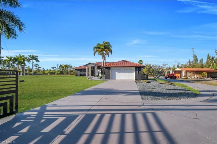 View of front of home with concrete driveway, a front lawn, an attached garage, and a metal roof