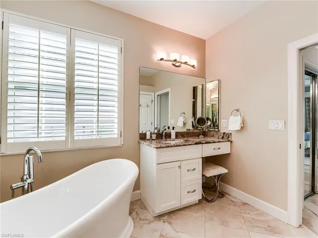 Bathroom with vanity, a freestanding tub, and healthy amount of natural light