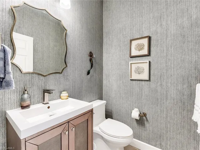 Half bath with vanity and wallpapered walls