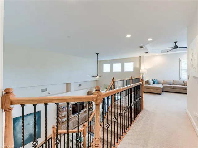 Corridor with an upstairs landing, recessed lighting, carpet flooring, a tray ceiling, and ornamental molding