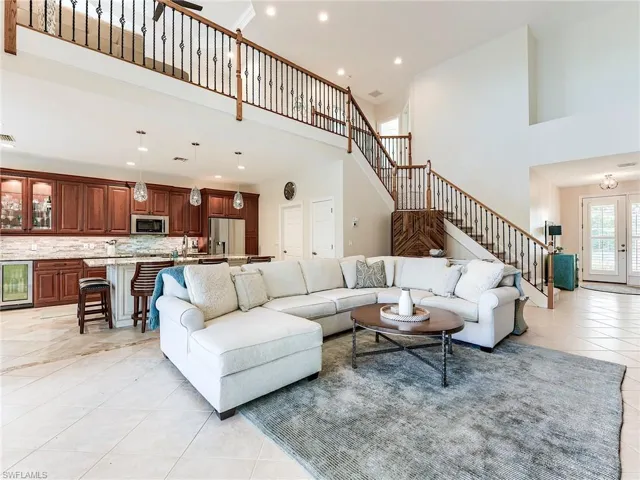 Living room with light tile patterned flooring, stairway, a high ceiling, wine cooler, and recessed lighting