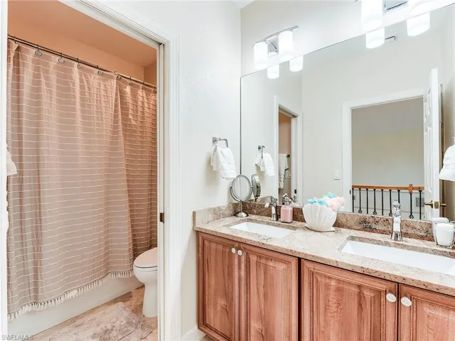 Bathroom with double vanity, shower / bath combo with shower curtain, and light tile patterned floors