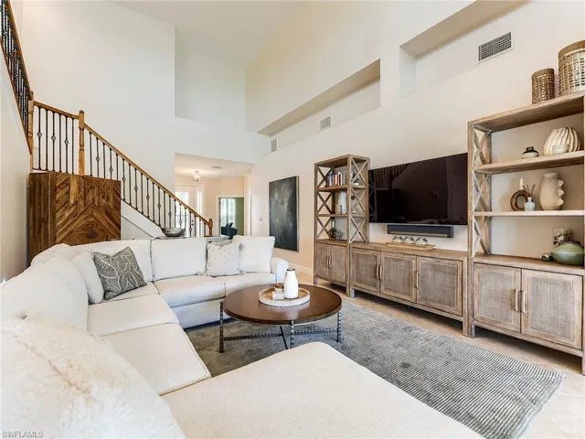 Living room with a towering ceiling, light tile patterned floors, and stairs