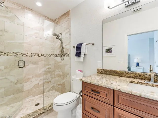 Bathroom with a stall shower, vanity, and a textured wall