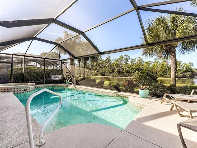 View of swimming pool featuring a lanai, a pool with connected hot tub, a patio, and a water view