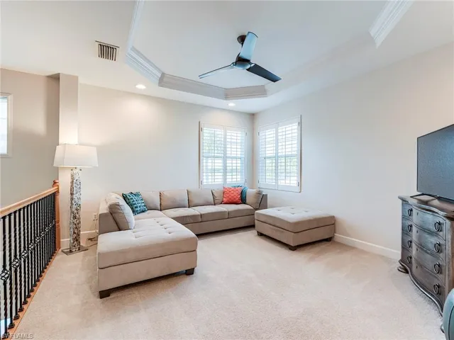 Living area featuring crown molding, carpet floors, a tray ceiling, recessed lighting, and a ceiling fan