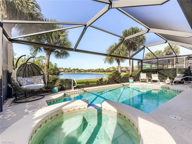 View of swimming pool with a lanai, a sunroom, a water view, a patio area, and a pool with connected hot tub