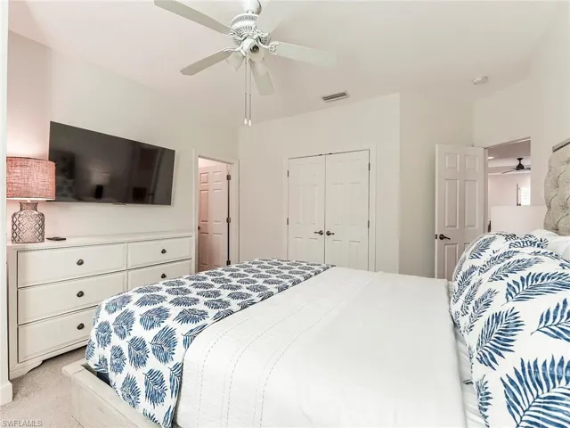 Carpeted bedroom featuring ceiling fan and a closet