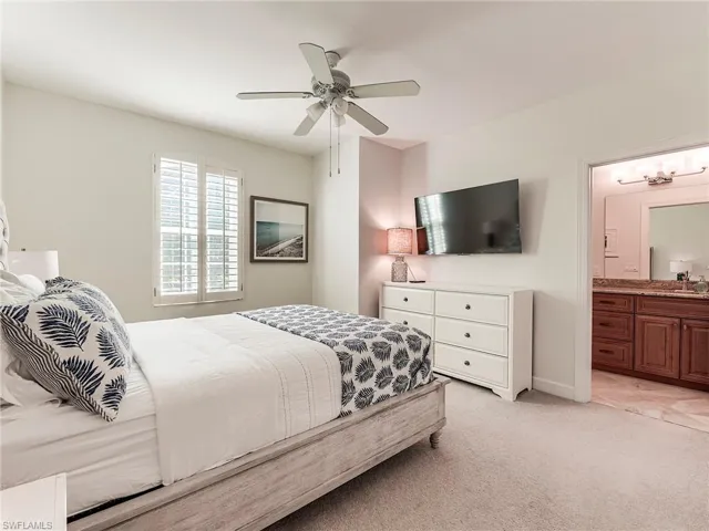 Guest bedroom 2 upstairs featuring en suite bathroom, light colored carpet, and a ceiling fan