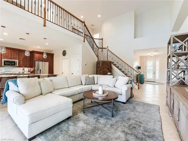 Living room featuring light tile patterned floors, stairway, a towering ceiling and recessed lighting