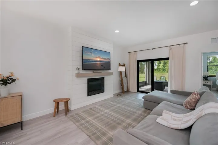 Living area with light wood-type flooring, a large fireplace, and recessed lighting