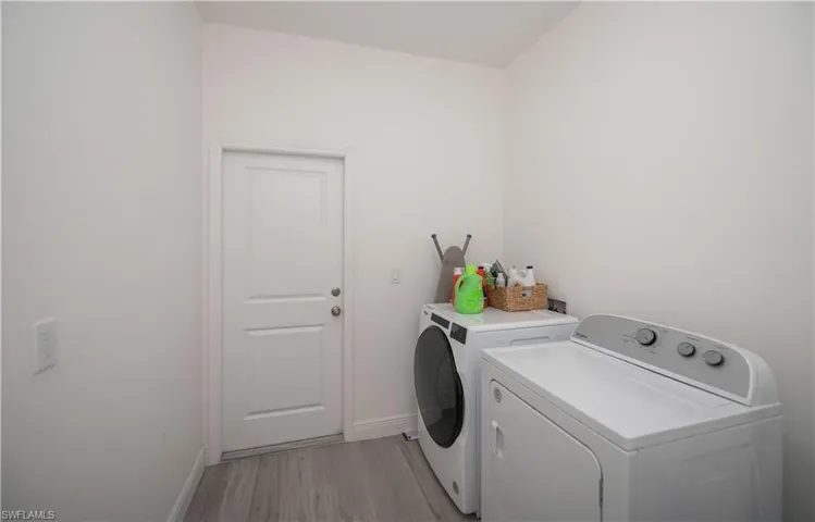 Laundry room featuring washing machine and clothes dryer and light wood finished floors