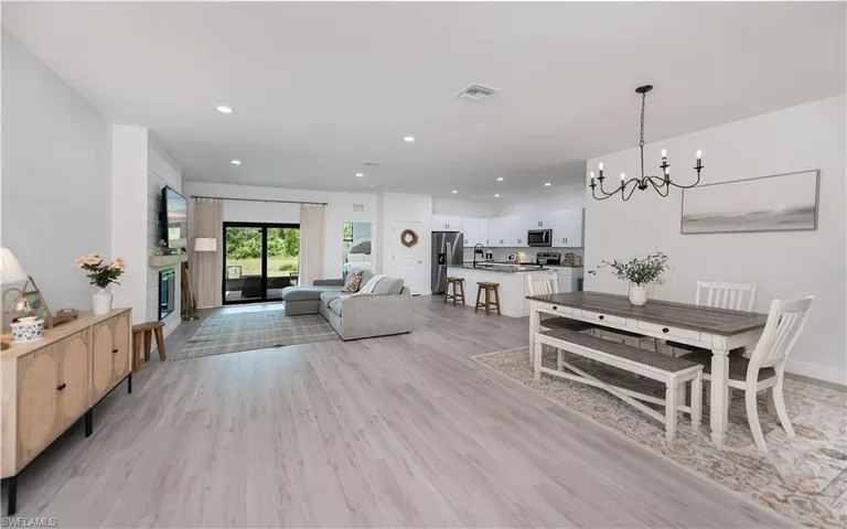 Dining room with a chandelier, light wood-style floors, and a glass covered fireplace