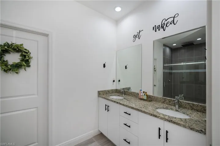Full bathroom featuring double vanity, a shower stall, and recessed lighting