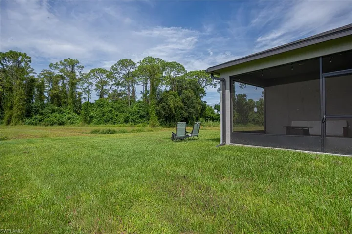 View of grassy yard featuring a sunroom