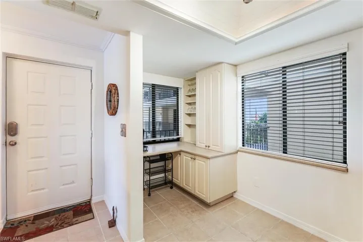 Foyer featuring plenty of natural light, light tile patterned floors, and crown molding