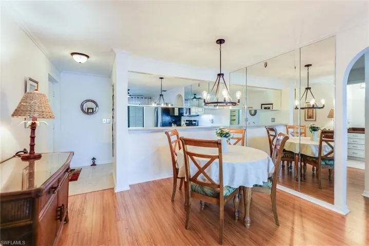 Dining space featuring ornamental molding, wood finished floors, arched walkways, and a chandelier