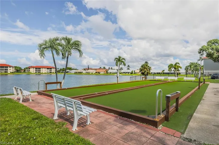 Surrounding community with a water view, a game area, a residential view, and a lawn