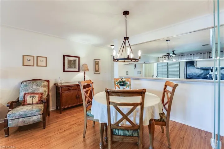 Dining area with wood finished floors, crown molding, and a chandelier