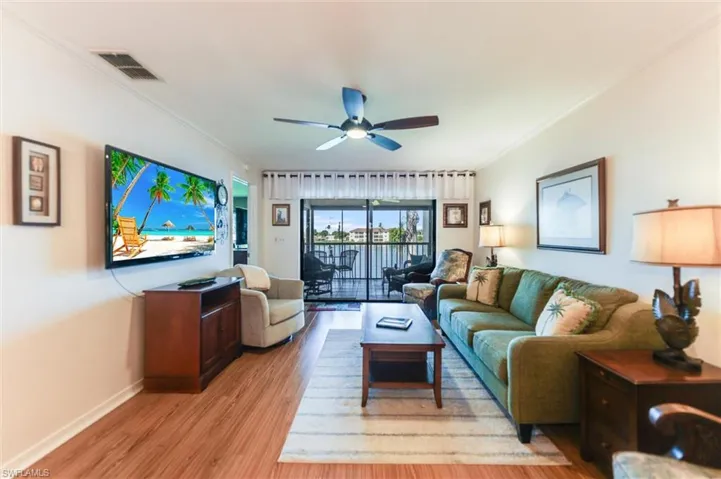 Living room featuring ornamental molding, light wood-type flooring, and ceiling fan