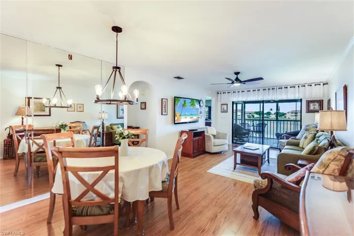 Dining area featuring a chandelier, light wood-style flooring, ceiling fan, ornamental molding, and arched walkways