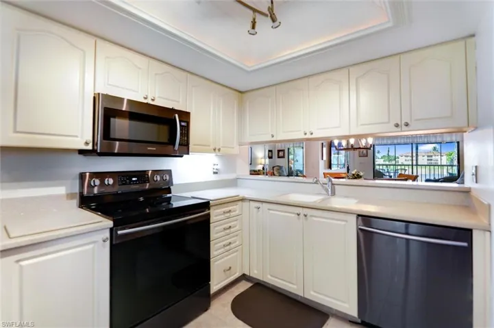 Kitchen with stainless steel appliances, light countertops, white cabinets, and a chandelier