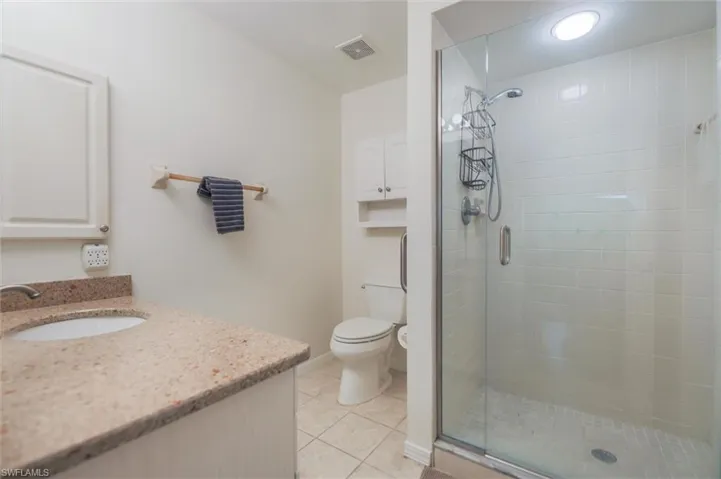 Full bath featuring a stall shower, vanity, and light tile patterned floors