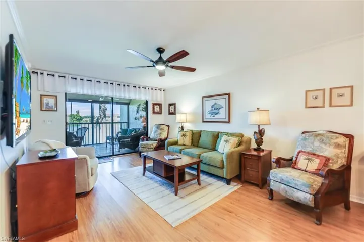 Living room with light wood-style floors, crown molding, and a ceiling fan